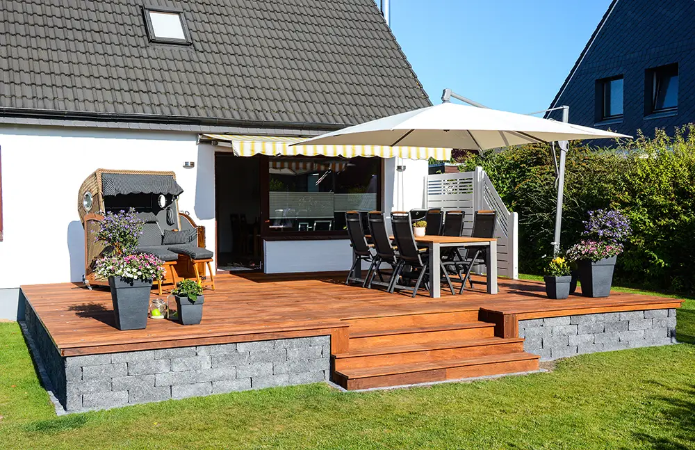 Holzterrasse mit Blockstufen und Steinbegrenzung im gepflegten Garten – professioneller Terrassenbau im Raum Ahrweiler